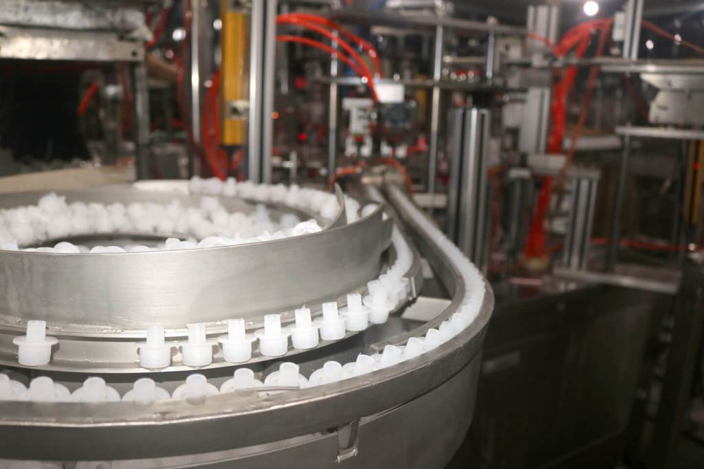 Automated assembly line feeds caps for air freshener bottles